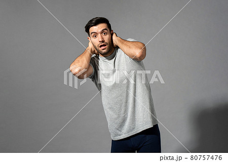 Surprised young Caucasian man gasping with hands behind neck 80757476