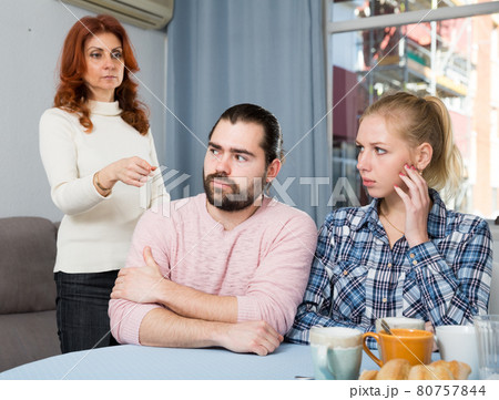 Portrait of sad mature woman trying to talk with adult children in home Portrait of sad mature woman trying to talk with adult children in home 80757844