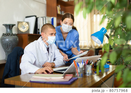Head in protective mask gives task to assistant at office 80757968