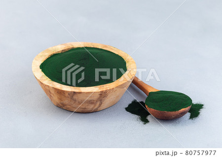 Chlorella powder superfood in wooden bowl and spoon, on gray background, horizontal 80757977