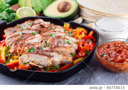 Chicken Fajitas with bell pepper and onion in a pan, served with salsa Asada, sour cream, avocado and tortillas, horizontal Chicken Fajitas with bell pepper and onion in a pan, served with salsa Asada, sour cream, avocado and tortillas, horizontal 80758013