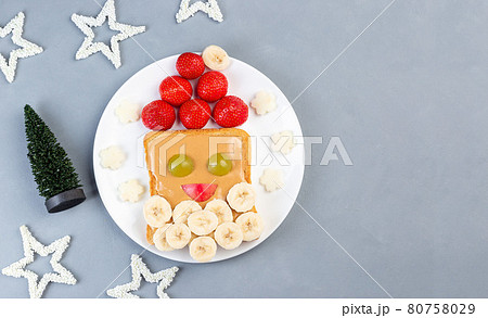 Christmas menu for kids, sandwich with Santa made from toast, peanut butter, strawberry, banana, grape and apple, horizontal, top view, copy space 80758029