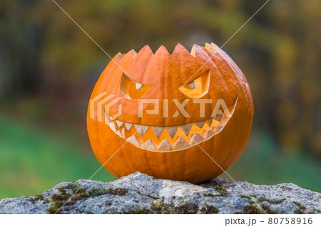 Scary smiling face halloween pumpkin on a stone Scary smiling face halloween pumpkin on a stone 80758916