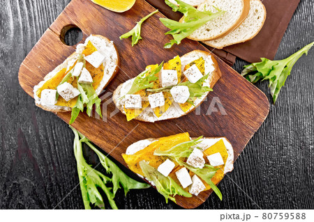 Bruschetta with pumpkin and arugula on wooden board top Bruschetta with pumpkin and arugula on wooden board top 80759588
