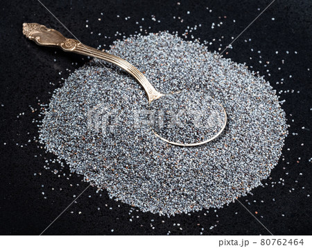 tablespoon in pile of poppy seeds on black plate tablespoon in pile of poppy seeds on black plate 80762464