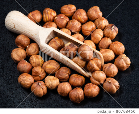 wood scoop on shelled hazelnuts on black plate wood scoop on shelled hazelnuts on black plate 80763450