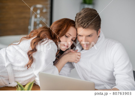 Ginger woman in a white bathrobe and her husband looking happy and in love 80763903