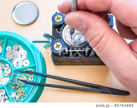 watchmaker adjusts mechanical watch by screwdriver 80764889