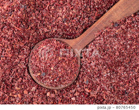 wood spoon on pile of sumac powder closeup 80765450