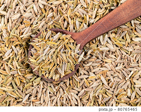 top view of wood spoon on pile of cumin seeds 80765465