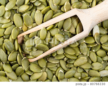 top view of wooden scoop on peeled pumpkin seeds 80766330