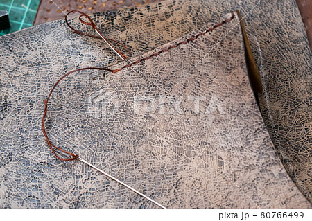 needles with thread near stitch on leather handbag 80766499