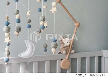 Baby crib mobile with stars, planets and moon. Kids handmade toys above the newborn crib. First baby eco-friendly toys made from felt and wood on gray background. Space for text. 80766715
