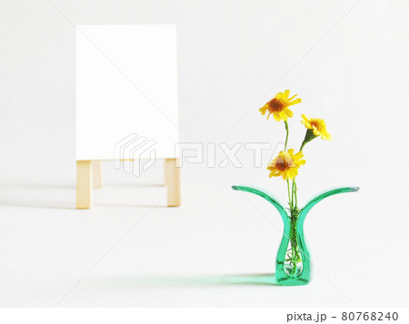 プラスチッククリップに挟んだ黄色い花と白色の立て看板のコピースペース 80768240