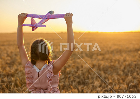 Happy child, girl playing with toy airplane on summer wheat field 80771055