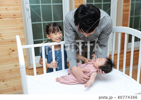 新生児を抱っこしてベッドに寝かしつけをするパパ 80774366