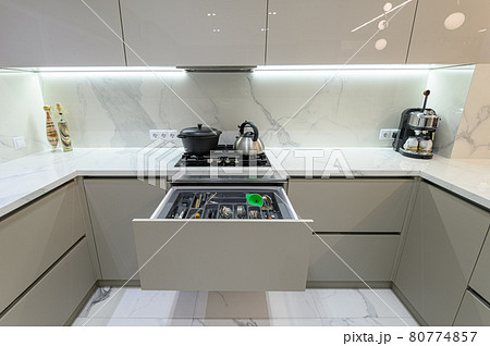 Open drawer with cutlery at modern white woden kitchen in classic style 80774857