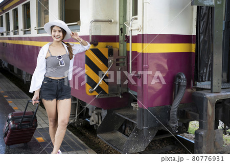Asian woman traveler with suitcase waiting for train at railway station. 80776931