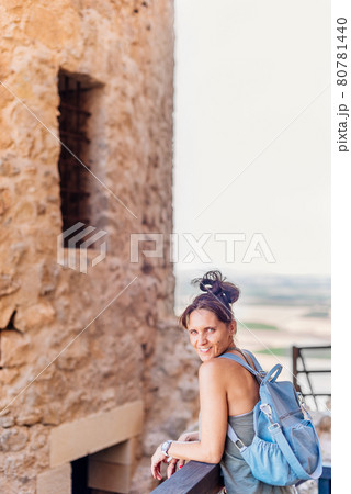 Woman leaning on a railing next to historic castle 80781440