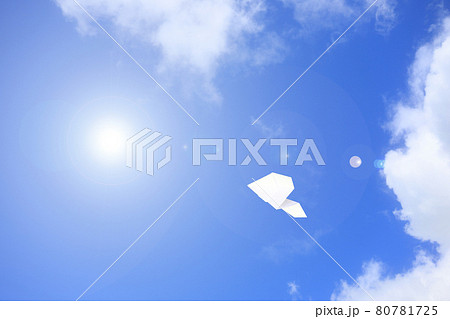 大空を飛ぶ紙飛行機の写真素材
