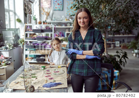 Flourist shop with different kinds of dryed flowers. Young happy confident specialist is working with her female kid. 80782402