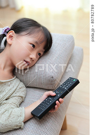 ソファに寝転んでテレビを見る幼児の女の子 80782789