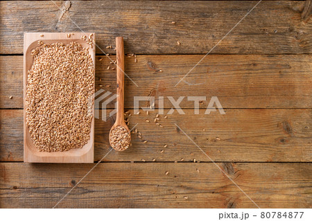 Wholegrain uncooked raw spelt farro on wooden plate on the wooden table 80784877
