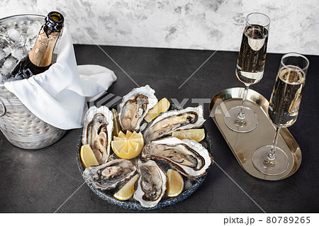 Champagne glasses with sparkling wine and bottle in bucket near oysters Champagne glasses with sparkling wine and bottle in bucket near oysters 80789265