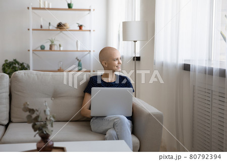 Dreamy young relaxed hairless sitting at home with computer. 80792394