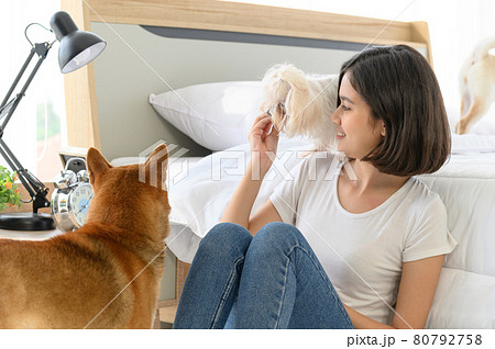 Young Asian woman relaxing and playing with three dogs (brown shiba inu, white shiba puppy and white maltese)in bedroom at home, Cheerful and nice couple with people and pet. Pet Lover concept 80792758