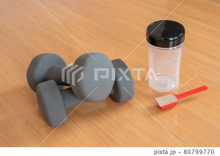 2個のグレーのダンベルとシェーカーとプロテインの入ったスプーン 80799770