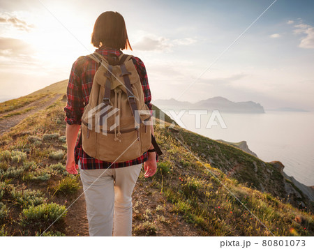 A young Asian woman with a backpack hiking in the summer. 80801073