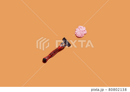 Shaving foam gel and razor on orange background. A multiple use shaving razor and cream. View from above 80802138