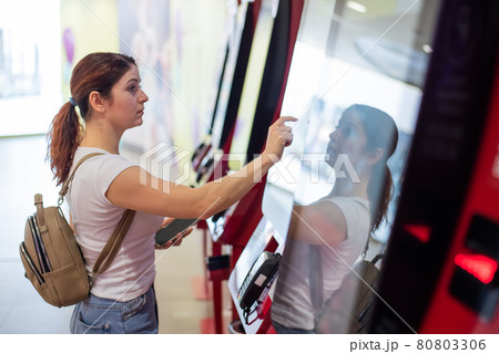Caucasian woman buying cinema ticket at self-service box office. Caucasian woman buying cinema ticket at self-service box office. 80803306
