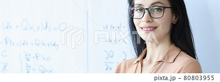 Woman teacher with glasses stands near white board 80803955