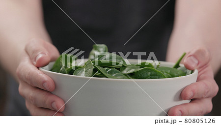 man show fresh spinach leaves in white bowl closeup 80805126