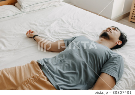 Tired man is lying on the bed as he out of energy. Tired man is lying on the bed as he out of energy. 80807401