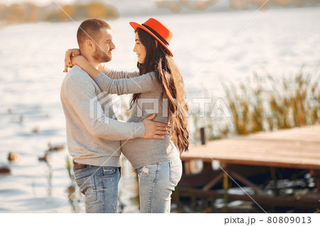 Pregnant wife with her husband standing near river 80809013