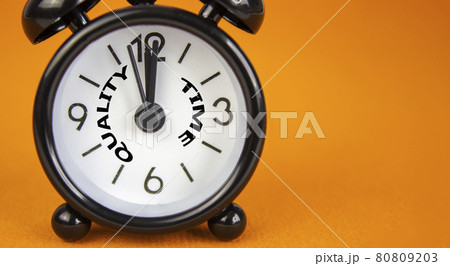 Quality time symbol. Beautiful black alarm clock with words 'quality time'. Beautiful orange background. Copy space. Business and quality time concept. Quality time symbol. Beautiful black alarm clock with words 'quality time'. Beautiful orange background. Copy space. Business and quality time concept. 80809203
