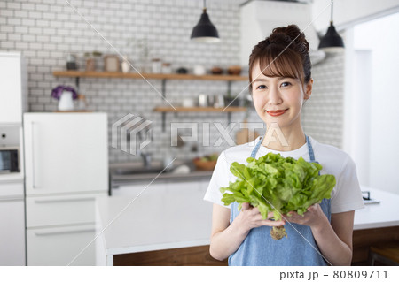 キッチンで野菜を持つエプロンの女性 80809711