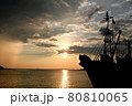 夕日を受けてシルエットの漁船、雨が虹色のカーテンに 80810065