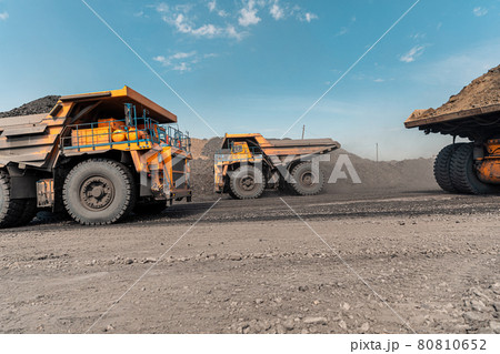Large quarry dump truck. Big yellow mining truck at work site. Loading coal into body truck. Production useful minerals. Mining truck mining machinery to transport coal from open-pit production 80810652
