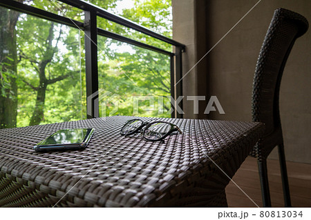 森に臨むバルコニーとガーデンファニチャー　スマホと眼鏡 80813034