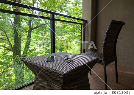 森に臨むバルコニーとガーデンファニチャー　スマホと眼鏡 80813035
