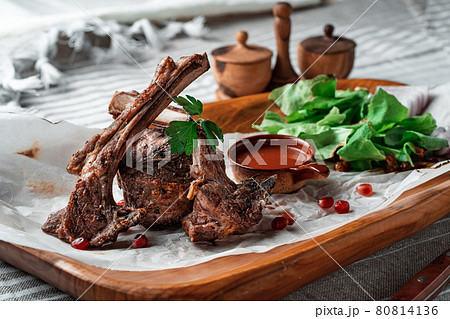 Grilled lamb loin on a wooden plate with lettuce leaves 80814136