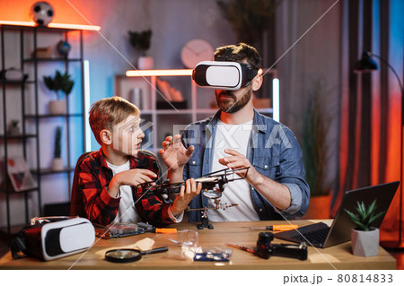 Boy with father fixing quadcopter in VR headset Boy with father fixing quadcopter in VR headset 80814833