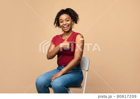 Young African American woman pointing at adhesive bandage on her arm, getting vaccinated against covid-19 80817209