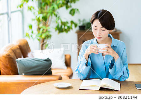 リビングでコーヒーを飲みながら読書をするミドルの女性 80821144