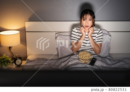 shocked woman watching TV movie on a bed at night shocked woman watching TV movie on a bed at night 80822531
