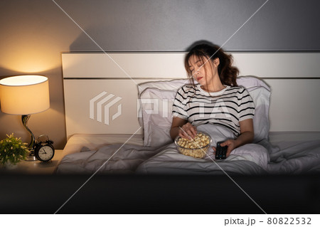 woman sleeping while watching tv on a bed at night 80822532